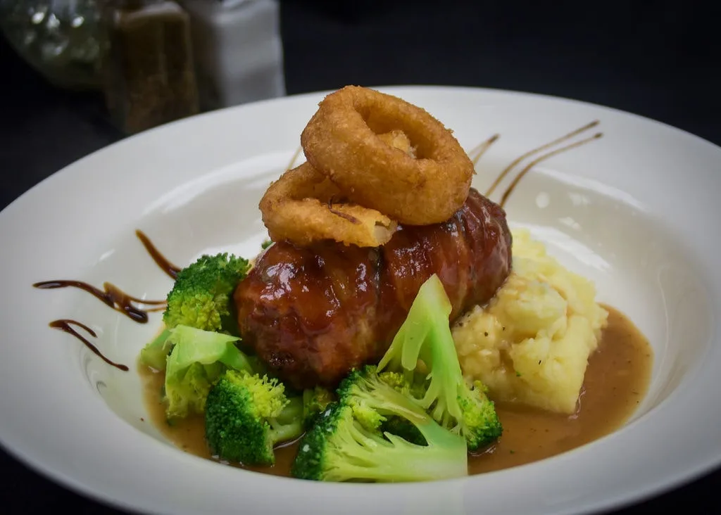 Savory bacon-wrapped meatloaf dinner served with steamed broccoli at Longley's.