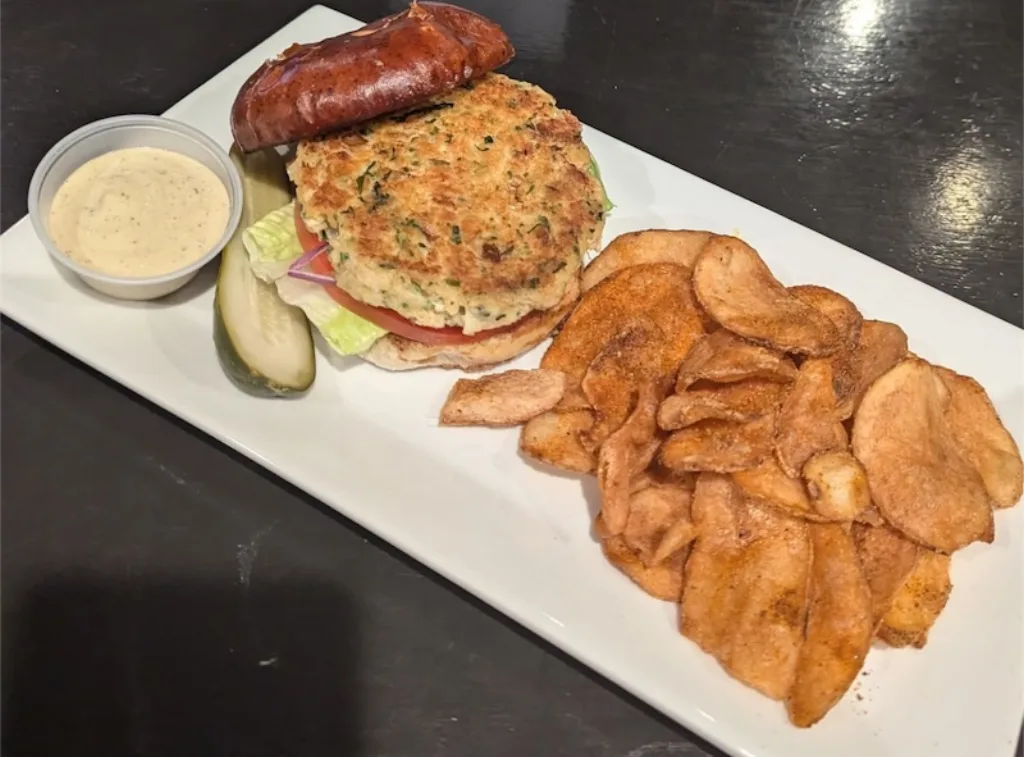 Crab cake sandwich served on a soft pretzel bun with chips at Longley's.
