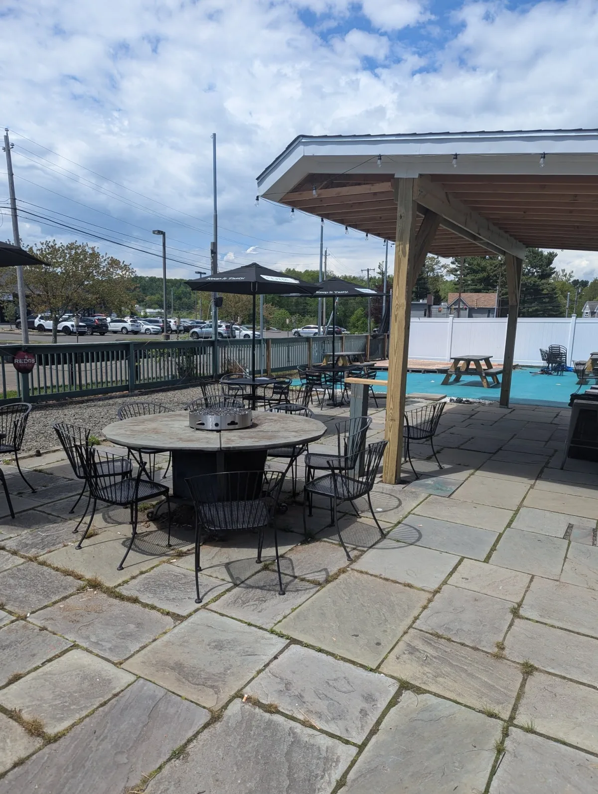 Stone patio with fire-pit table, umbrellas, and covered pavilion at Longley's in Branford CT.