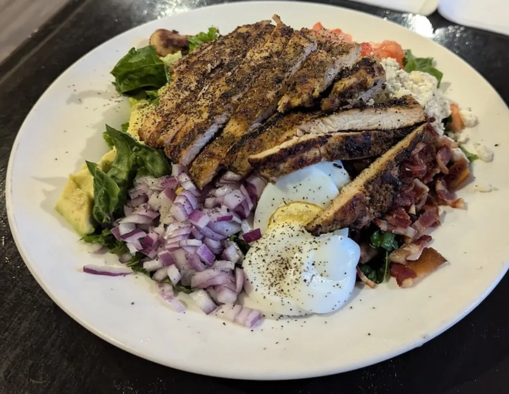 Sliced grilled chicken Cobb salad with bacon and avocado.