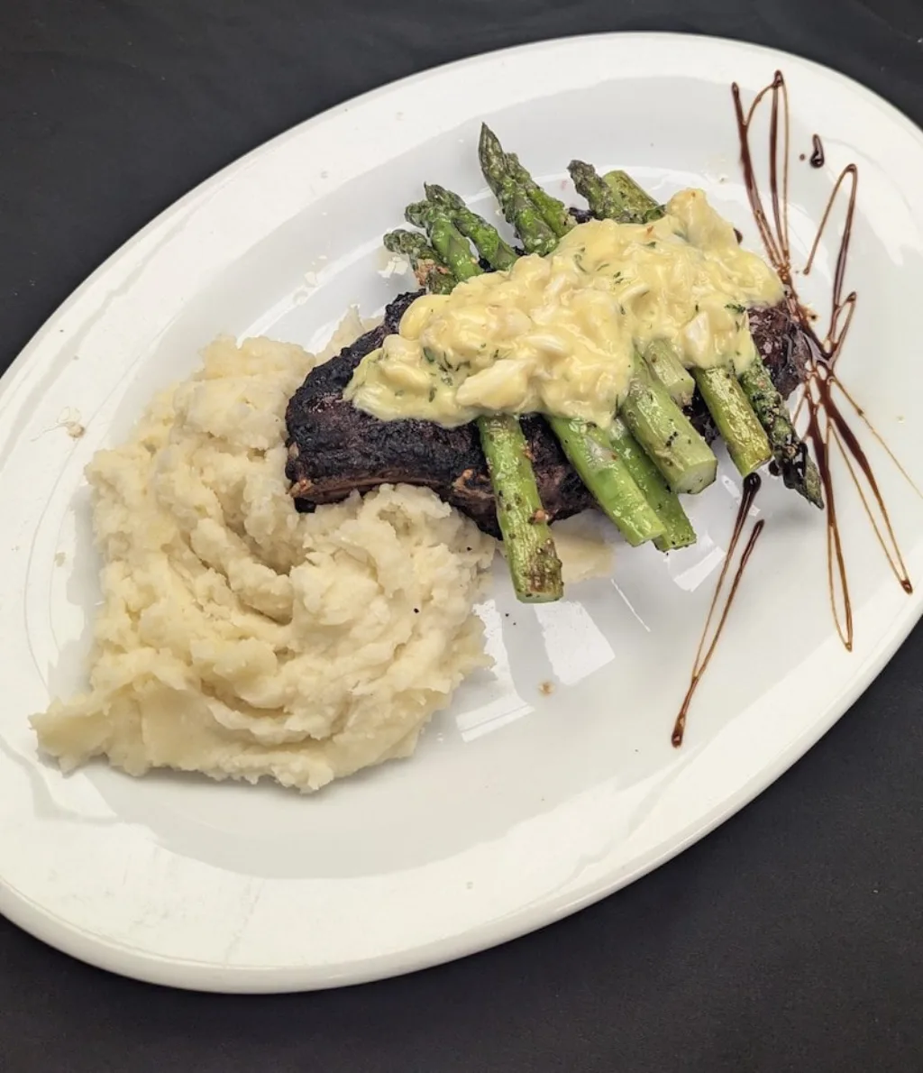 Luxurious Steak Oscar topped with crab meat and asparagus, served with mashed potatoes.